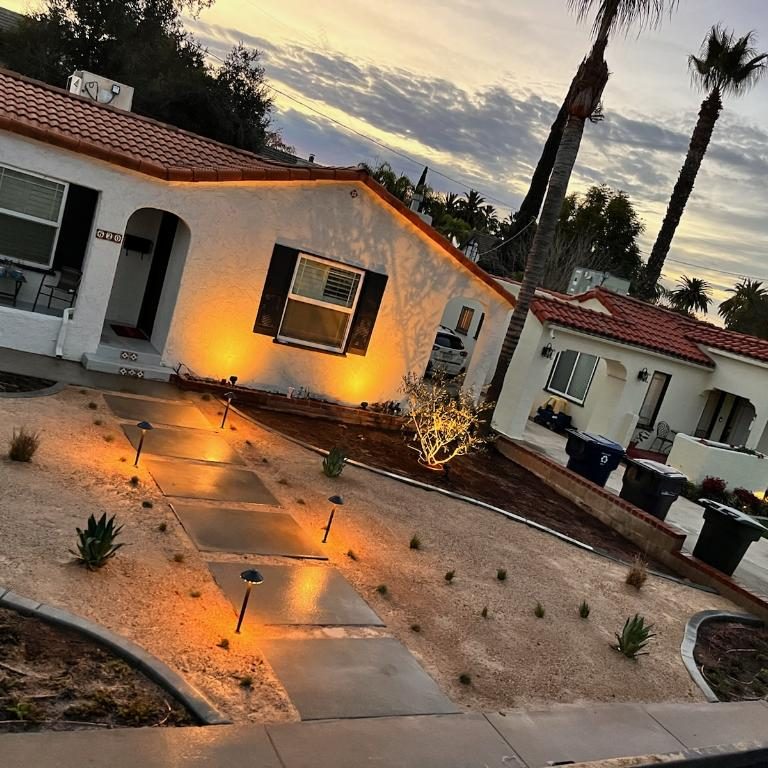 A front walkway of large pavers lit by landscape lights at dusk